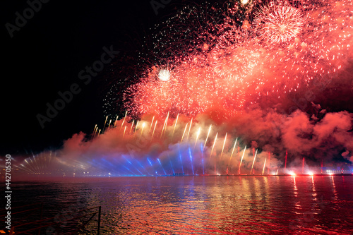 Fototapeta Naklejka Na Ścianę i Meble -  Festive colorful fireworks and illumination in dark sky with beautiful reflection in water. Holiday SCARLET SAILS. High quality photo