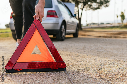 Driver putting red triangle near broken car photo