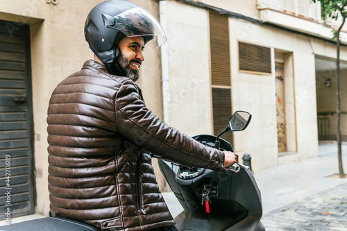 Hispanic motorcyclist driving modern bike on city street photo
