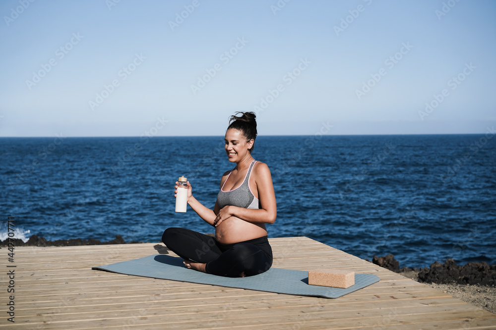 Young pregnant woman drinking water while doing yoga outdoor - Focus on face