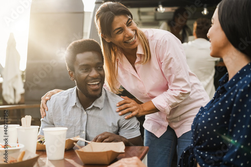 Multiracial people eating at food truck restaurant outdoor - Focus on center woman face