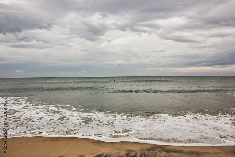 Scenic view of the waves hitting the beach on a cloudy overcast day in the village of Varkala in Kerala, India.