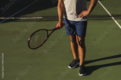 Midsection of senior african american man holding tennis racket on tennis court © WavebreakMediaMicro
