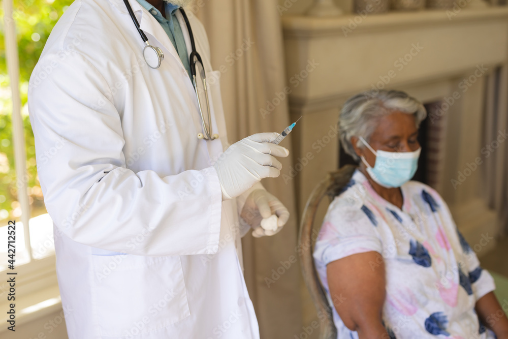 Senior african american woman in face mask receiving vaccination