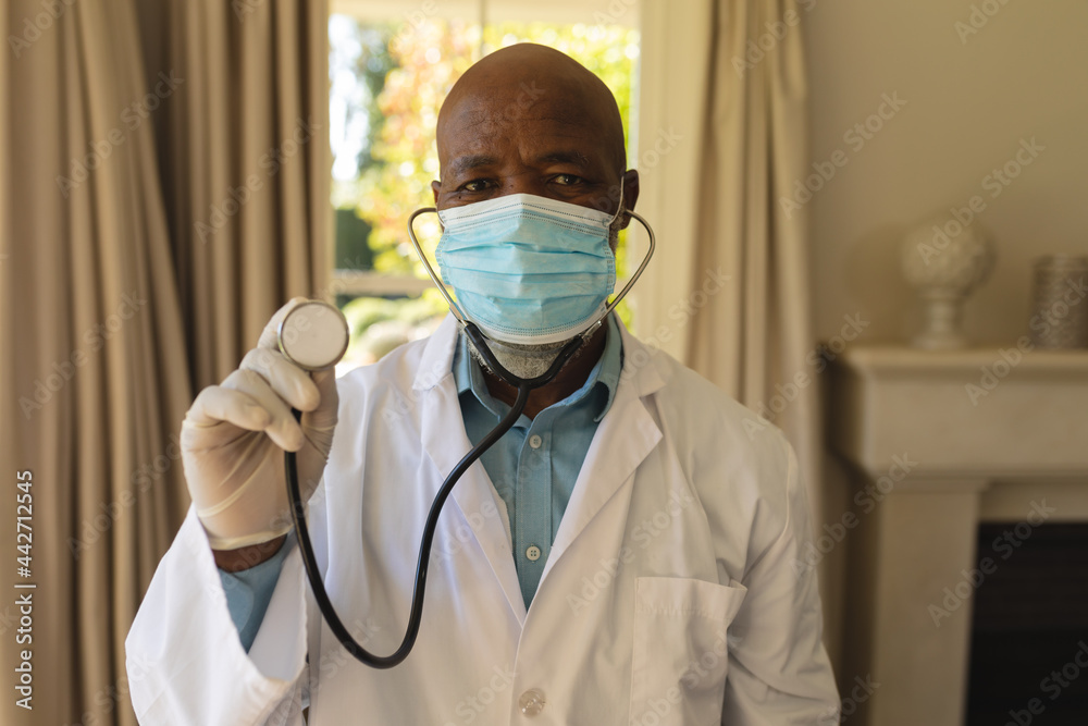 Portrait of senior african american male doctor in face mask holding stethoscope Portrait of senior african american male doctor in face mask holding stethoscope