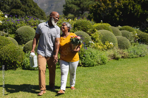 Canvas Print Senior african american couple spending time in sunny garden together walking an