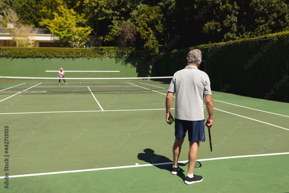 Senior caucasian couple playing tennis together on court
