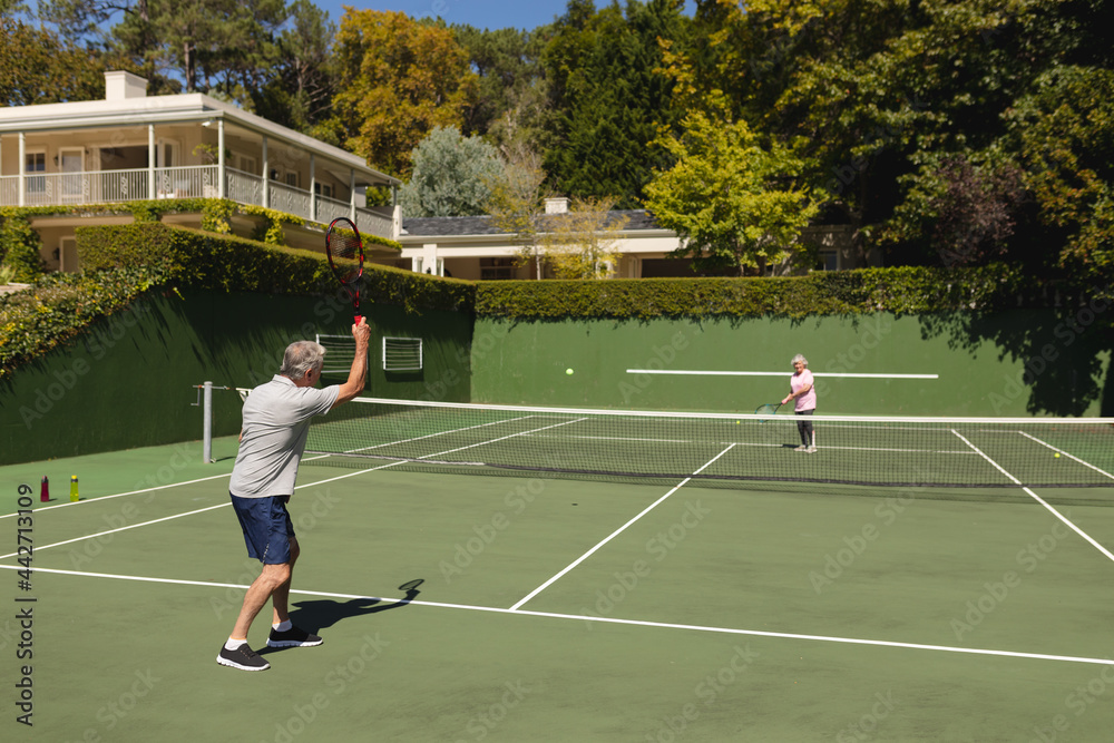 Obraz premium Senior caucasian couple playing tennis together on court
