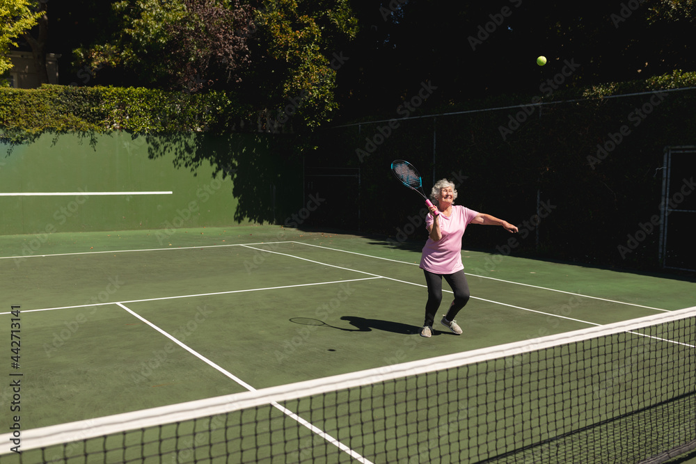 Senior caucasian woman playing tennis on court holding tennis racket