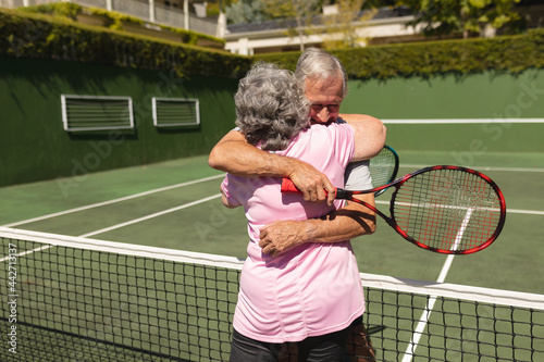 Senior caucasian couple playing tennis together on court embracing © wavebreak3