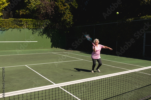 Senior caucasian woman playing tennis on court holding tennis racket