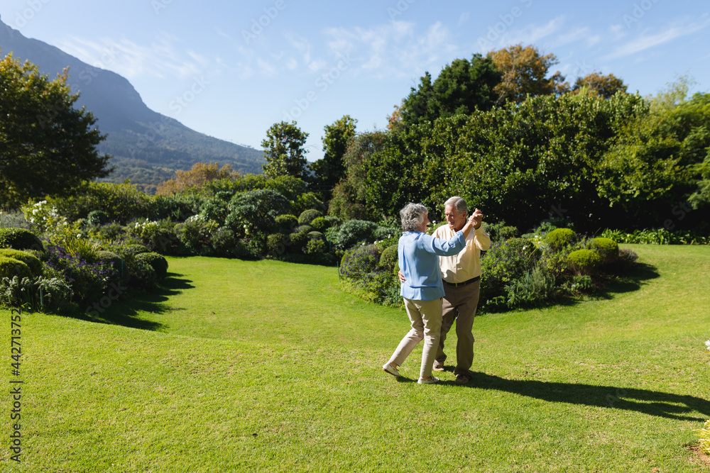 Senior caucasian couple dancing together in sunny garden