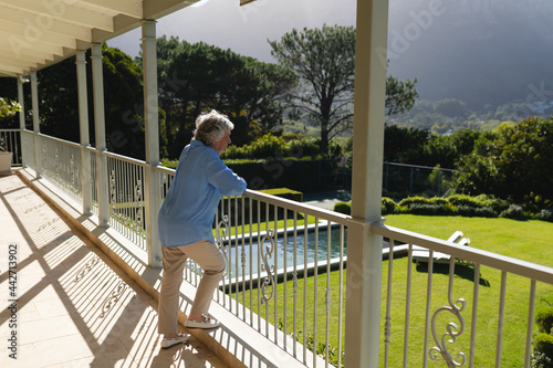 Senior caucasian woman standing on balcony and looking away