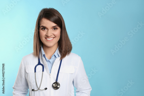 Pediatrician with stethoscope on light blue background  space for text