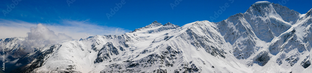 Panoramic view of the Caucasus Mountains from Cheget, height 3050 meters, Kabardino-Balkaria, Russia. Photo of snow-capped peaks against the blue sky.