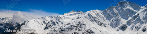 Panoramic view of the Caucasus Mountains from Cheget, height 3050 meters, Kabardino-Balkaria, Russia. Photo of snow-capped peaks against the blue sky. © lexosn