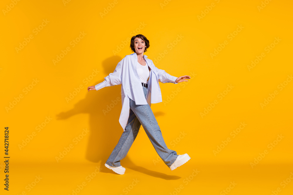 Full length body size photo of positive girl going forward cheerful careless isolated on vibrant yellow color background