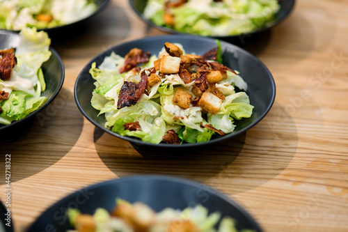 Selective focus of bowl of caesar salad placed on wooden table