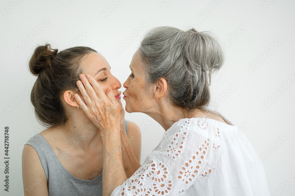Happy senior mother is hugging her adult daughter, the women are laughing together, sincere family of different age generations having fun on white background Happy senior mother is hugging her adult daughter, the women are laughing together, sincere family of different age generations having fun on white background