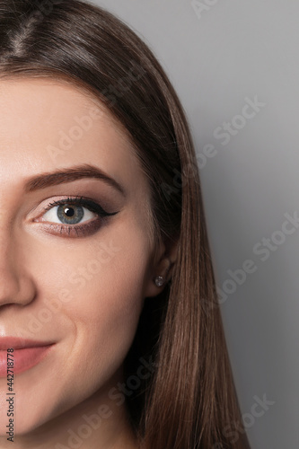 Beautiful woman with black eyeliner on grey background, closeup