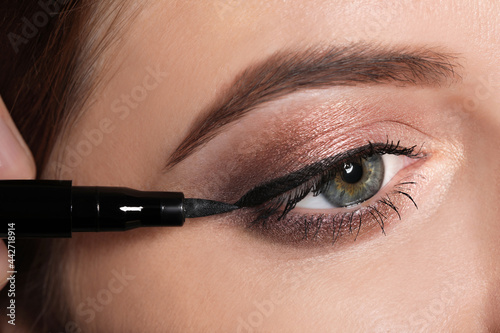 Artist applying black eyeliner onto woman's face, closeup