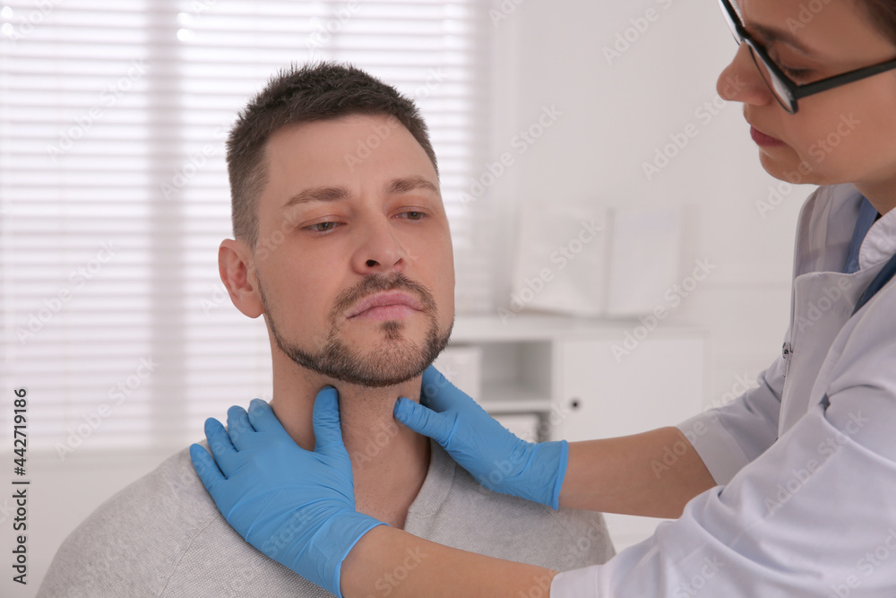 Fototapeta premium Doctor examining thyroid gland of patient in hospital