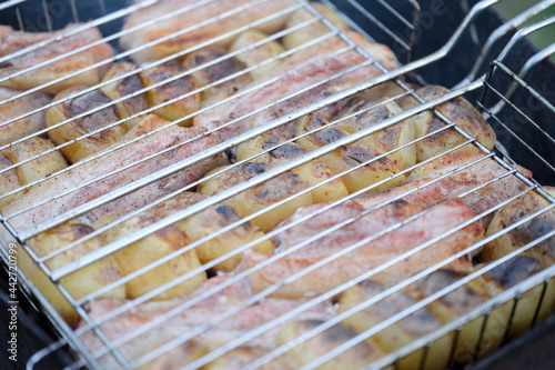 Roast pork and potatoes on wire rack over fire closeup