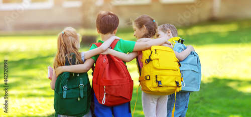 Group of children with rucksacks standing in the park near the school photo
