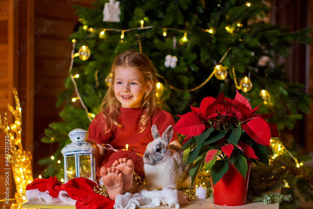 Merry Christmas happy holidays. Girl in white dress under tree with rabbit