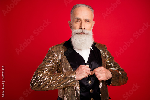 Portrait of attractive serious grey-haired man wearing blazer fixing buttons isolated over bright red color background photo