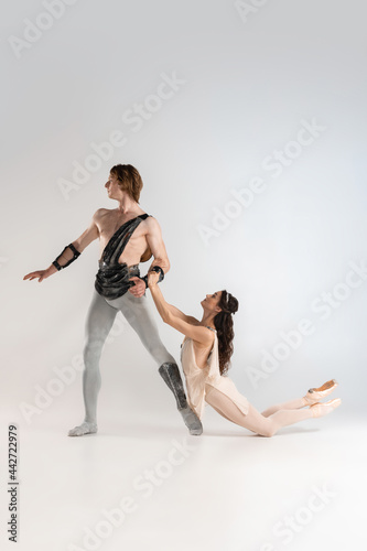 Young couple of ballet dancers in ancient Rome costumes dancing on white studio full of light. Historical character, classical art