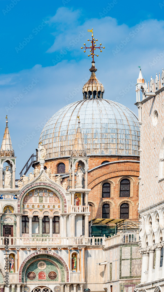 View over decoration elements at roofs and cupolas of Basilica San Marco in Venice, Italy, at sunny day and deep blue sky.