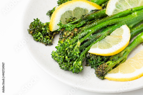 Cooked fresh broccolini with lemon on the plate photo