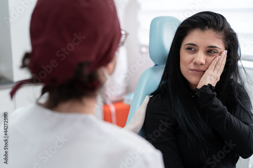Frowning woman with toothache in clinic photo