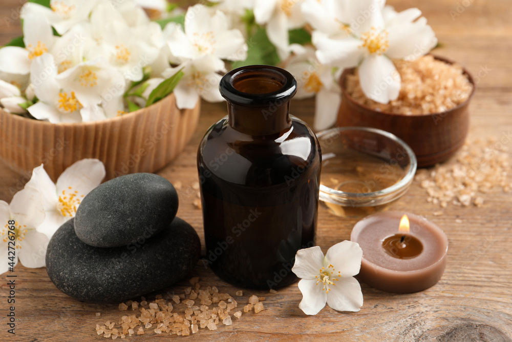 Beautiful composition with jasmine essential oil and fresh flowers on wooden table Beautiful composition with jasmine essential oil and fresh flowers on wooden table