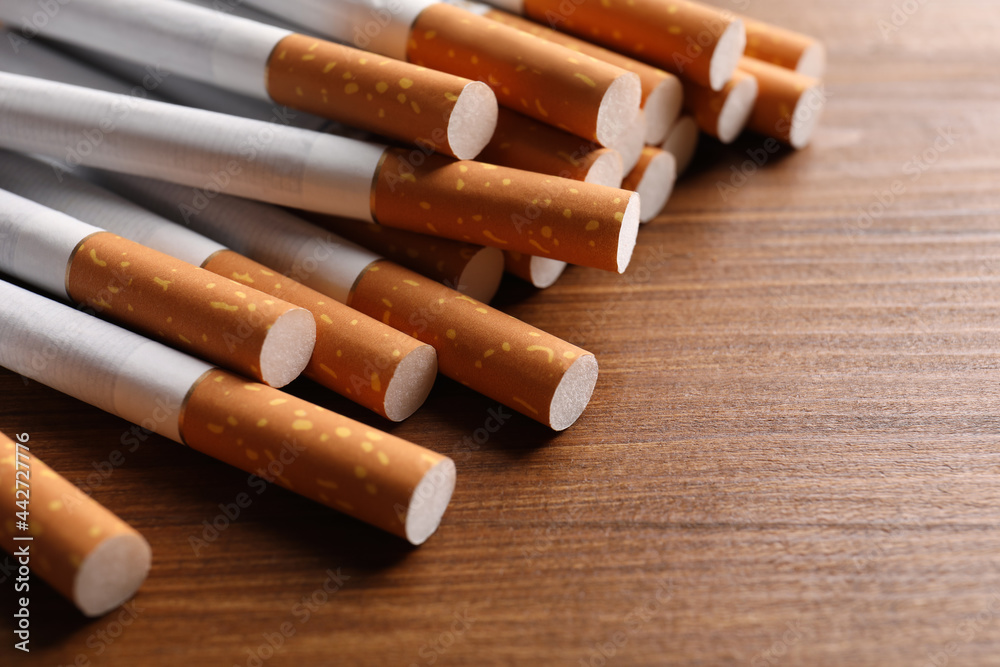 Pile of cigarettes on wooden table, closeup