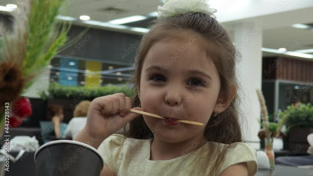 little cute girl drinking a cocktail or tea or coffee from a paper cup. happy, happy, loves sweets. Little girl eating cake ice cream in outdoor cafe little cute girl drinking a cocktail or tea or coffee from a paper cup. happy, happy, loves sweets. Little girl eating cake ice cream in outdoor cafe