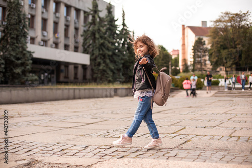 The little girl is walking around the city with a bag