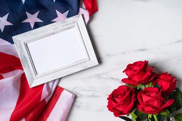 Concept of Independence day or Memorial day. Flag and rose over bright marble table background.