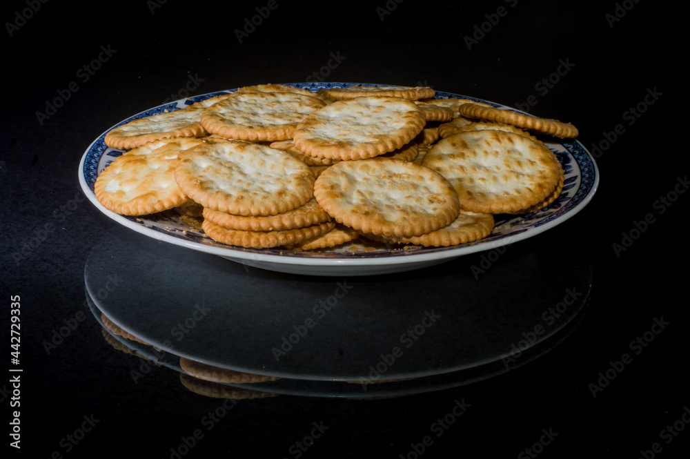 crackers on a plate with black background and copy space