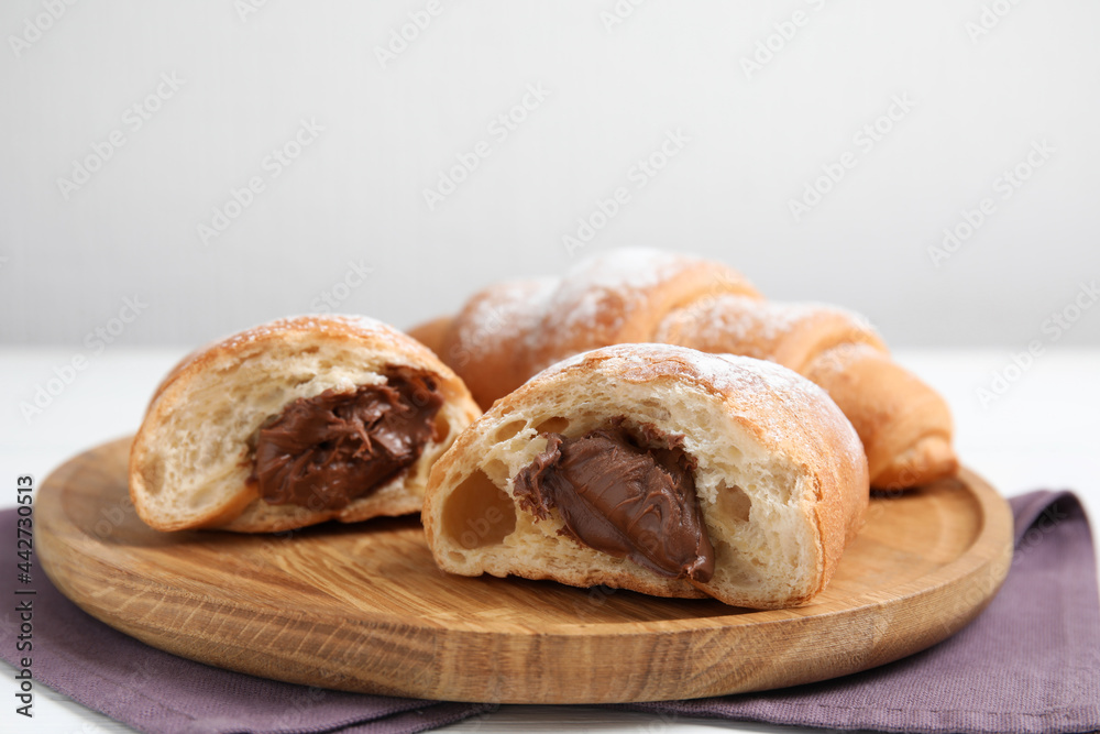 Fresh croissants with chocolate on wooden plate. Space for text