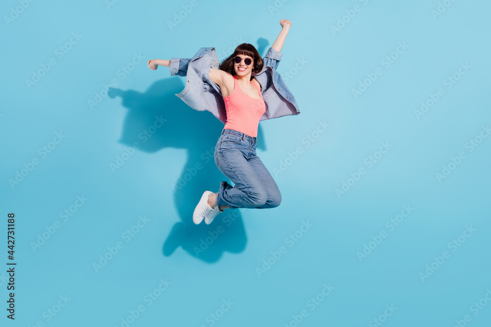 Obraz premium Full length body size view of pretty cheerful carefree girl having fun jumping isolated over bright blue color background