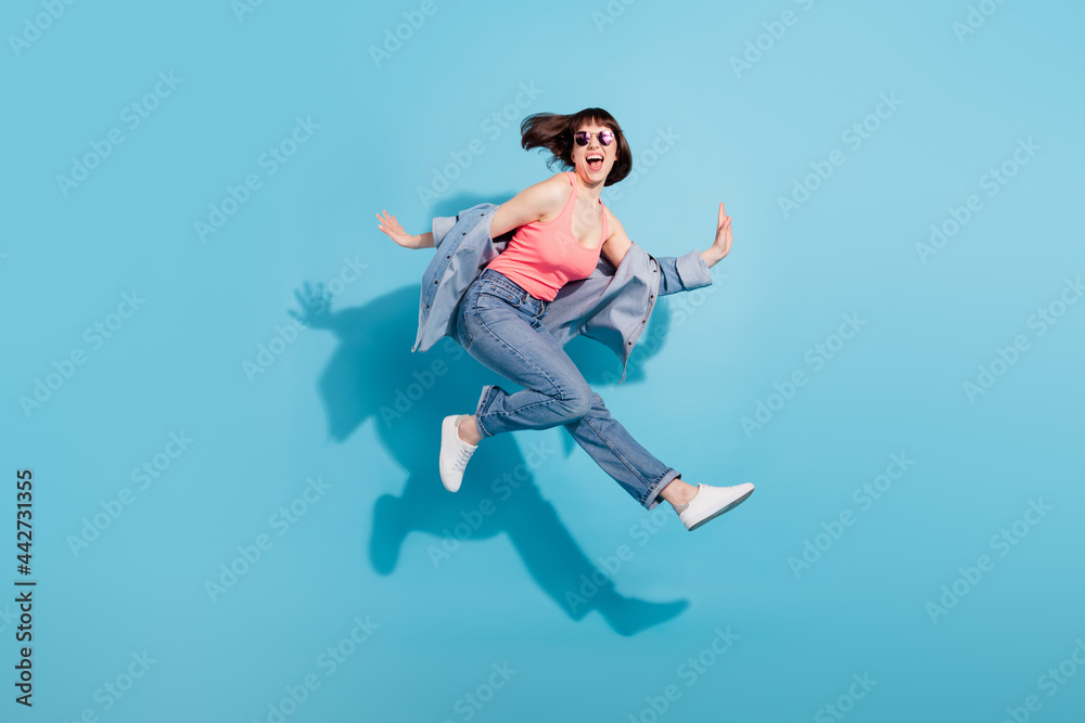 Full size profile photo of hooray young lady jump wear top jeans eyewear isolated on blue color background