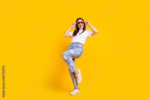 Fototapeta Naklejka Na Ścianę i Meble -  Full body photo of young excited girl happy positive smile hipster hands touch sunglass isolated over yellow color background