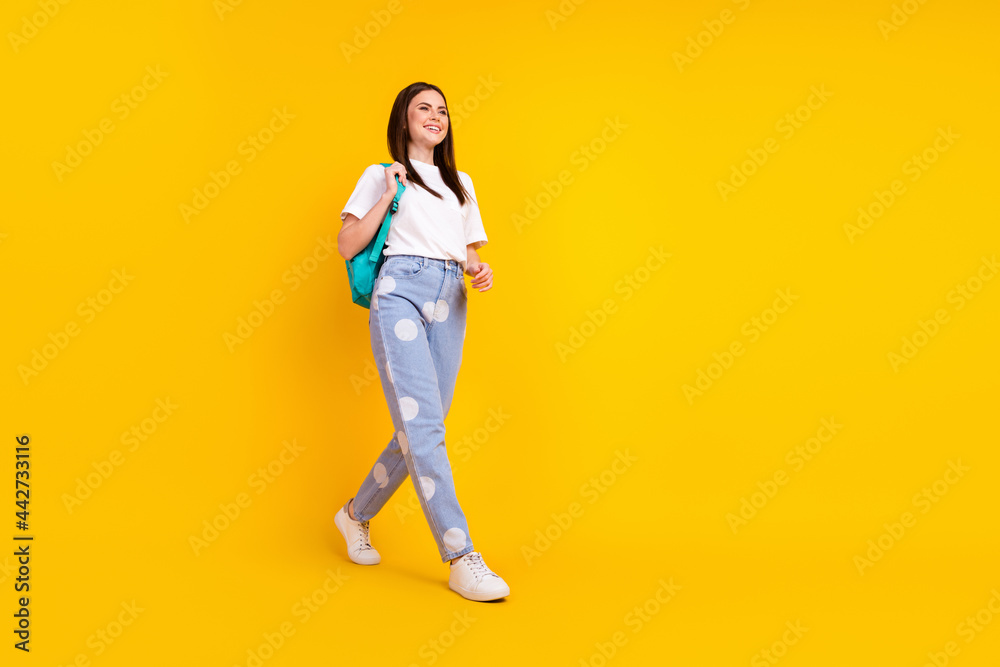 Full body profile side photo of young attractive girl happy positive smile go walk step backpack isolated over yellow color background Full body profile side photo of young attractive girl happy positive smile go walk step backpack isolated over yellow color background