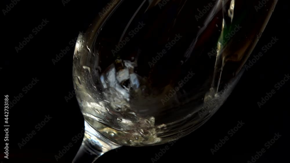Wine is poured into a glass on a black background. Slow motion. Wine is poured into a glass on a black background. Slow motion.
