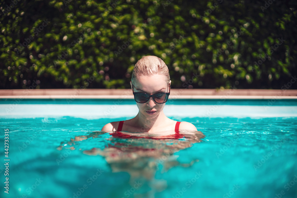 Young beautiful sexy girl enjoying swimming in the private pool and relaxing in the sun