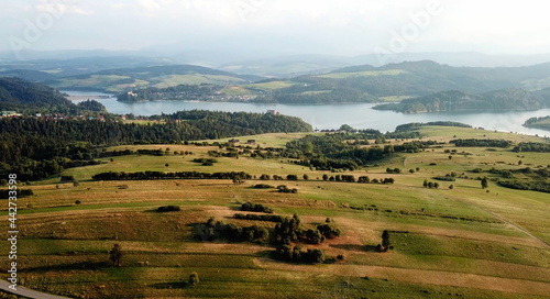 Mountain meadows with a lake and distant foggy highlands in the background