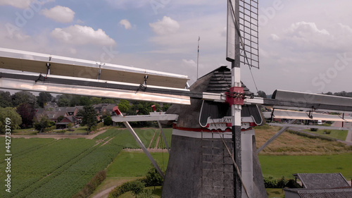 Dynamic side closeup view of traditional Dutch windmill with details of the wicks and mechanism against a blue sky with cumulus clouds. Aerial of countryside in The Netherlands photo