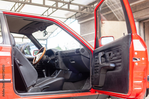 Interior of a red retro car, with a wooden steering wheel and open doors © Oleksii Nykonchuk